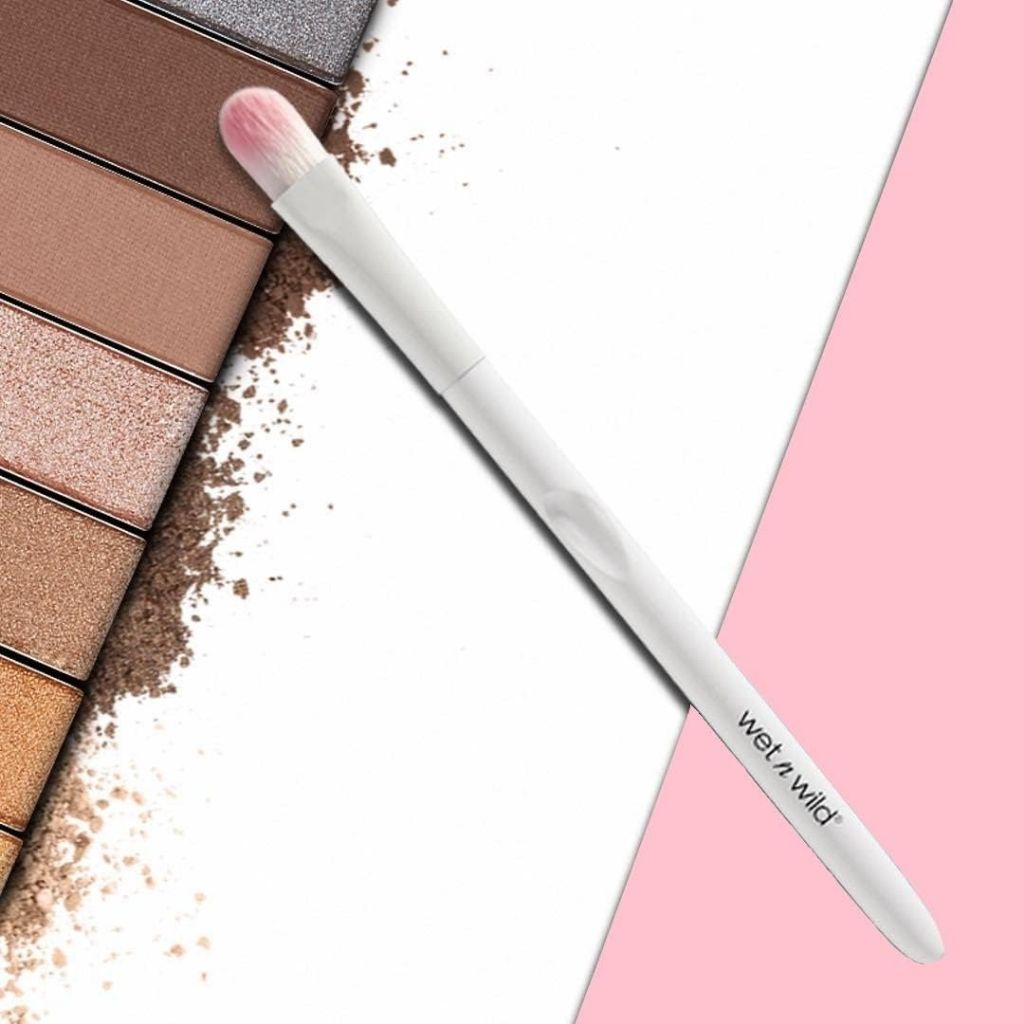 Makeup palette with shades of brown and beige, a brush, and a pink background.