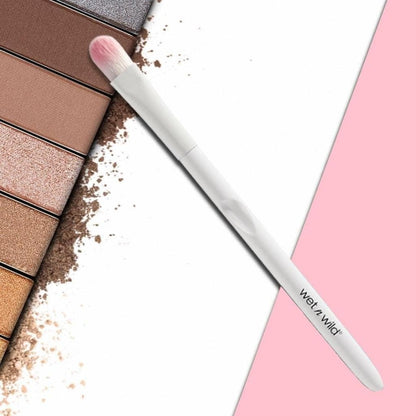 Makeup palette with shades of brown and beige, a brush, and a pink background.