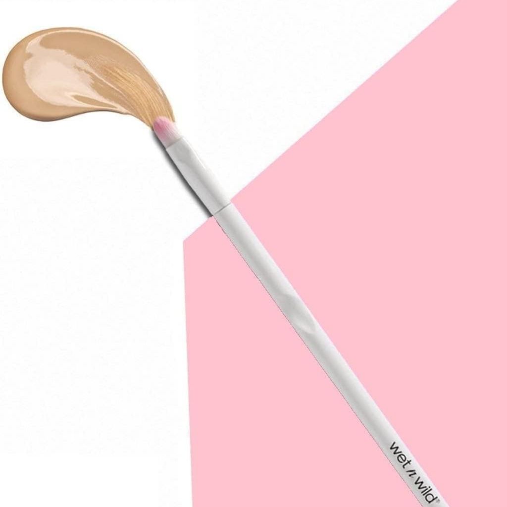 Makeup brush with beige powder on a pink background