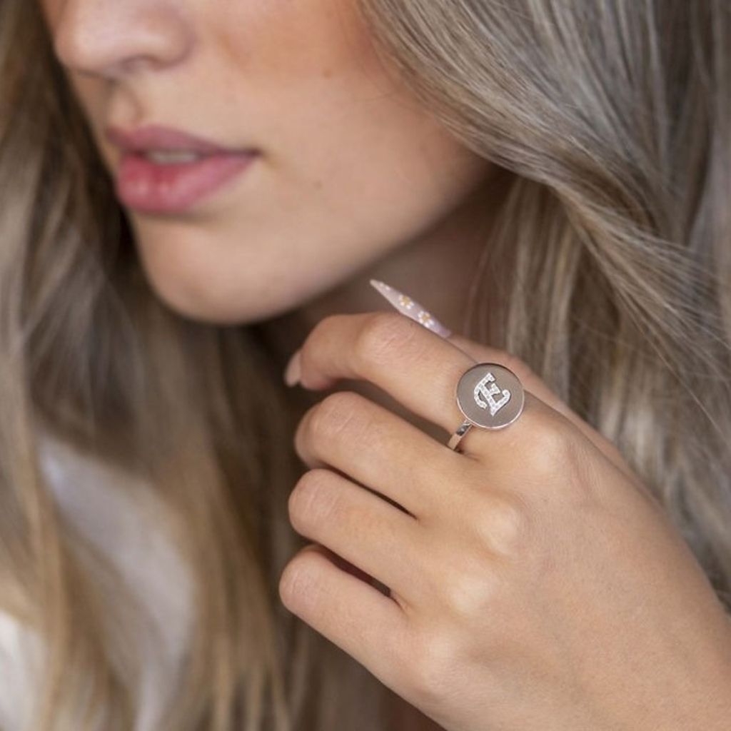 Close-up of a person wearing a silver ring with a circular design on their finger.