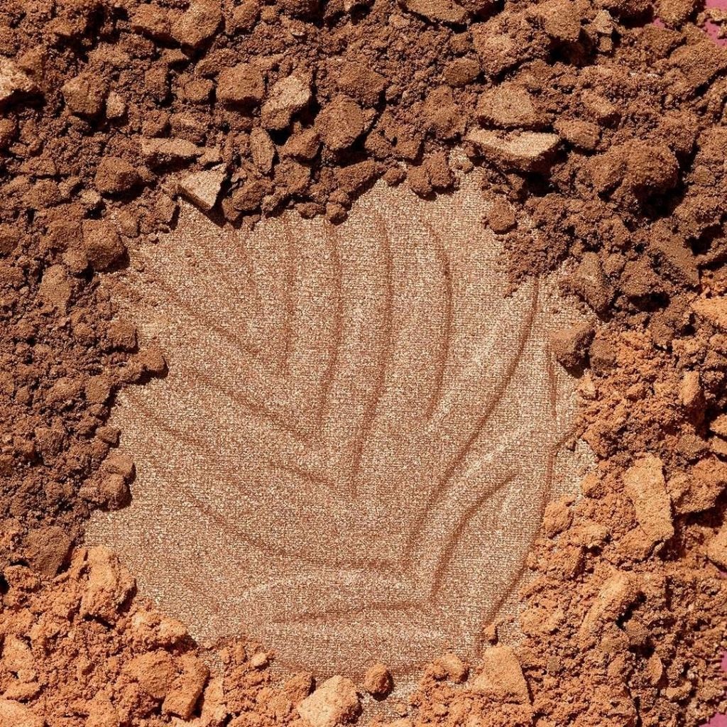 Close-up of a makeup product with a leaf pattern on a brown, textured background