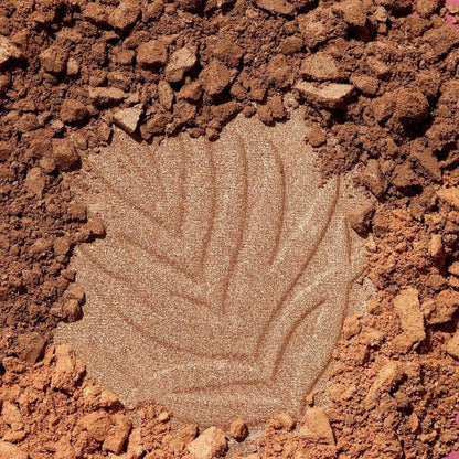 Close-up of a makeup product with a leaf pattern on a brown, textured background
