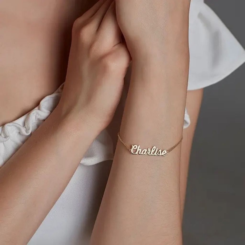 Gold bracelet with 'Charline' on a person's wrist against a neutral background