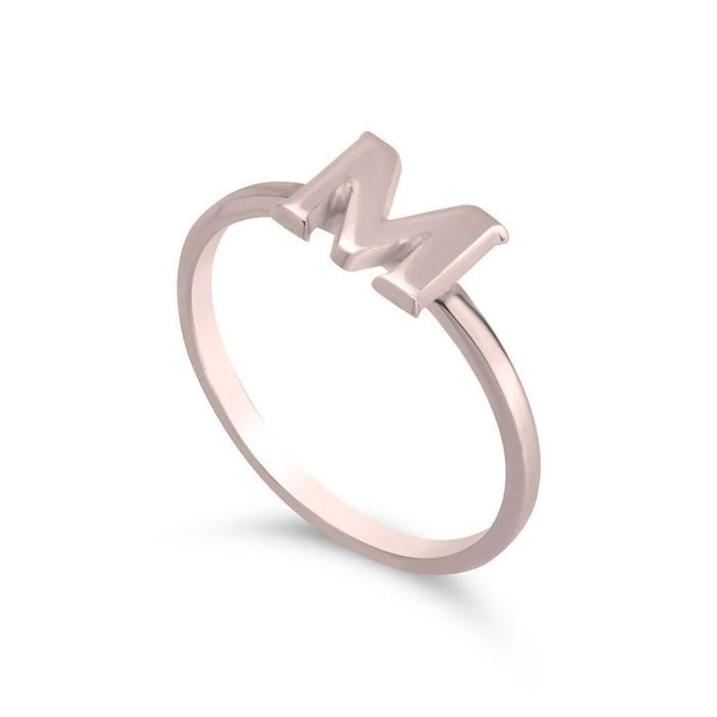 Rose gold ring with the letter 'M' on a white background