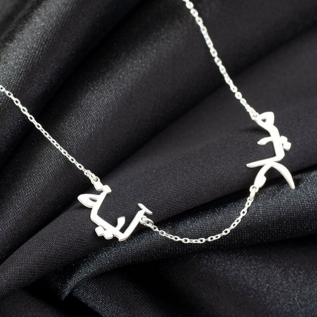 Silver necklace with leaf-like pendants on a black fabric background