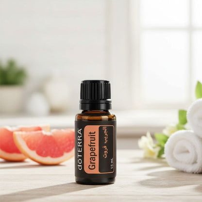 doTERRA Grapefruit essential oil bottle on a wooden surface with grapefruit and towels in the background.