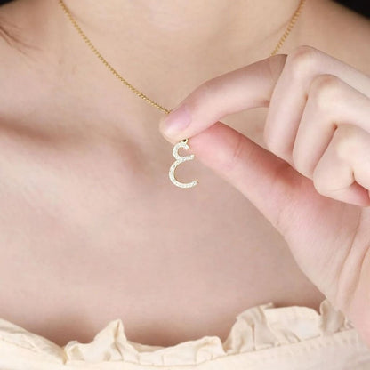 Gold necklace with a unique pendant held by a hand against a soft background