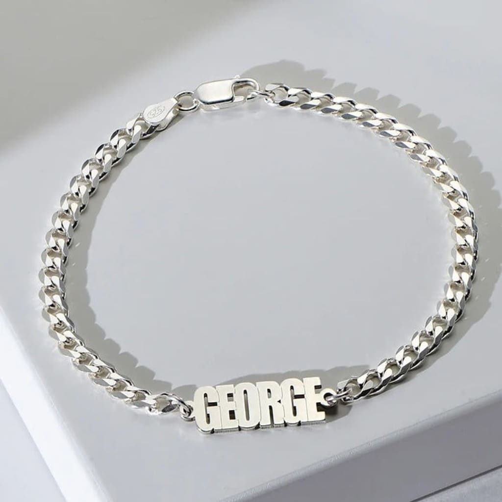 Silver chain bracelet with 'GEORGE' on a light gray background