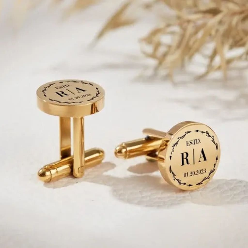 Gold cufflinks with engraved text on a light background