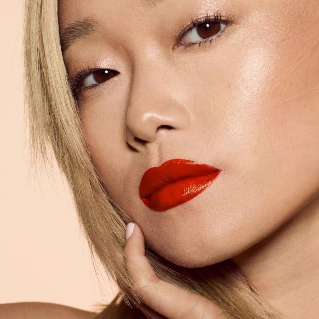 Close-up of a person with red lipstick on a beige background