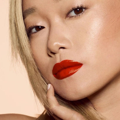 Close-up of a person with red lipstick on a beige background