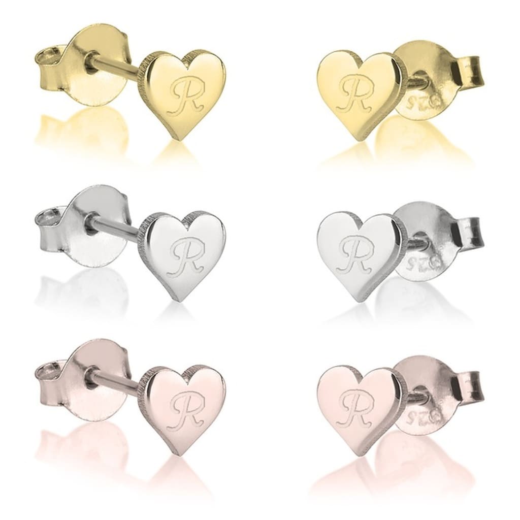 Set of heart-shaped earrings in gold, silver, and rose gold on a reflective surface.