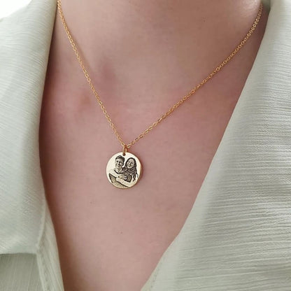 Gold necklace with a round pendant on a person wearing a light green top.