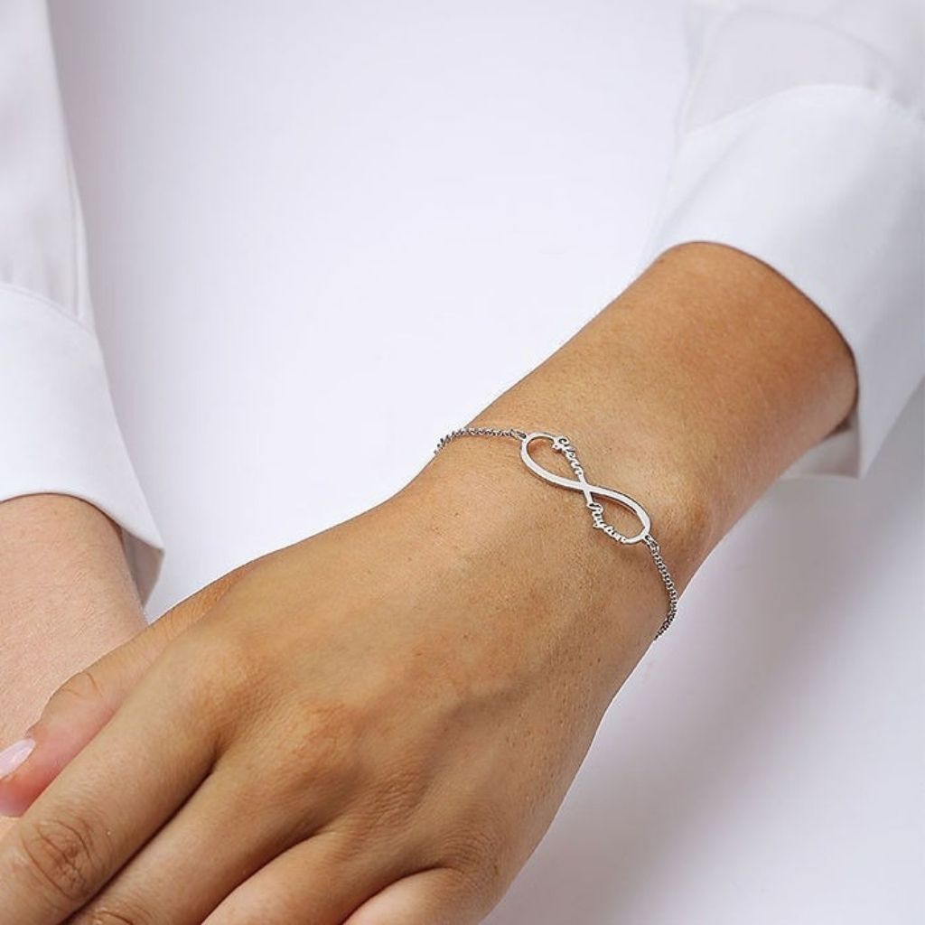 Silver infinity bracelet on a wrist with a white background
