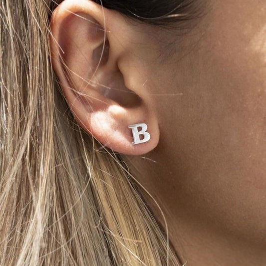 Silver letter 'B' earring worn by a person with blonde hair.
