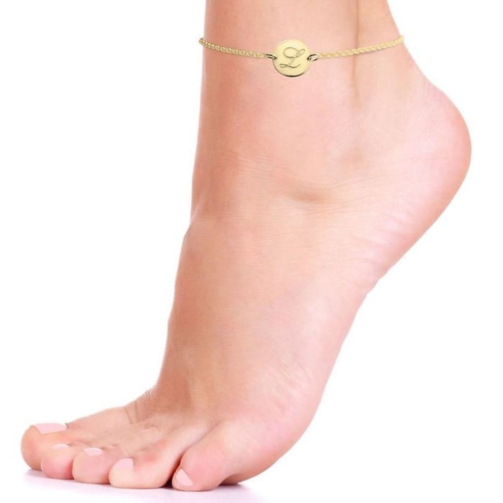 Gold anklet on a foot against a white background