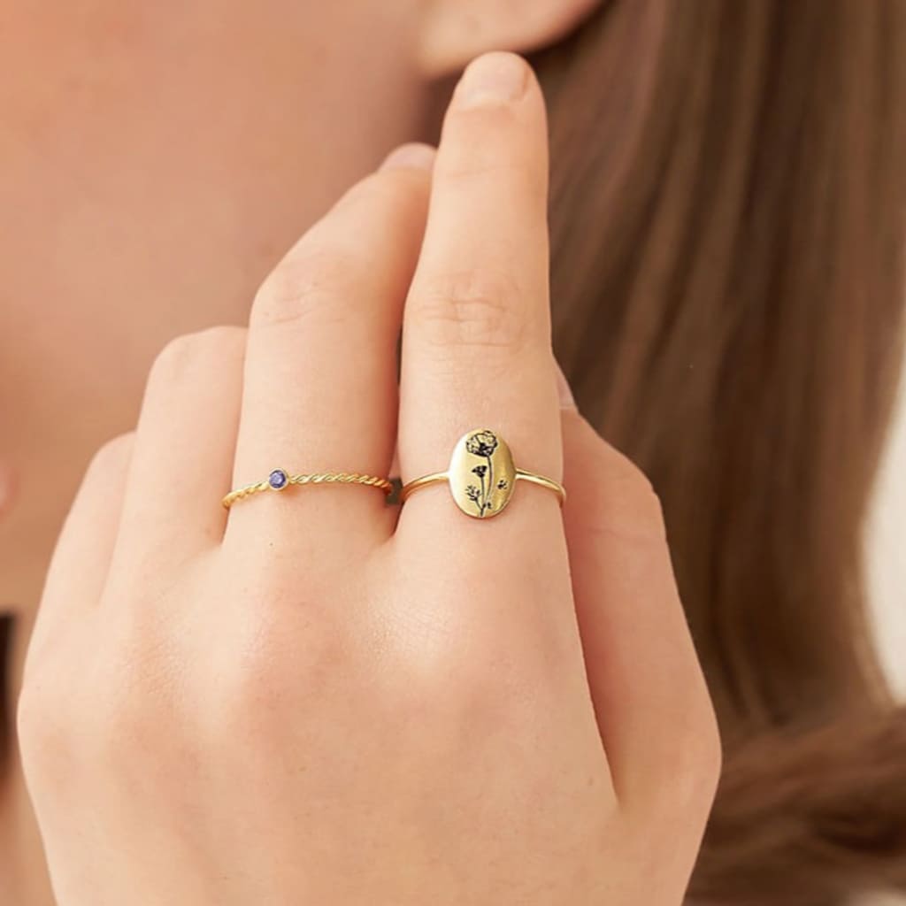 Close-up of a hand wearing two gold rings with a blurred background