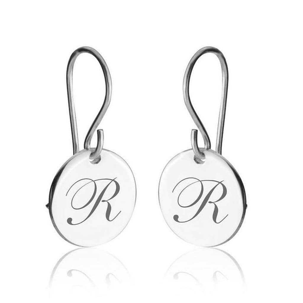 Pair of silver earrings with 'R' engraving on a white background