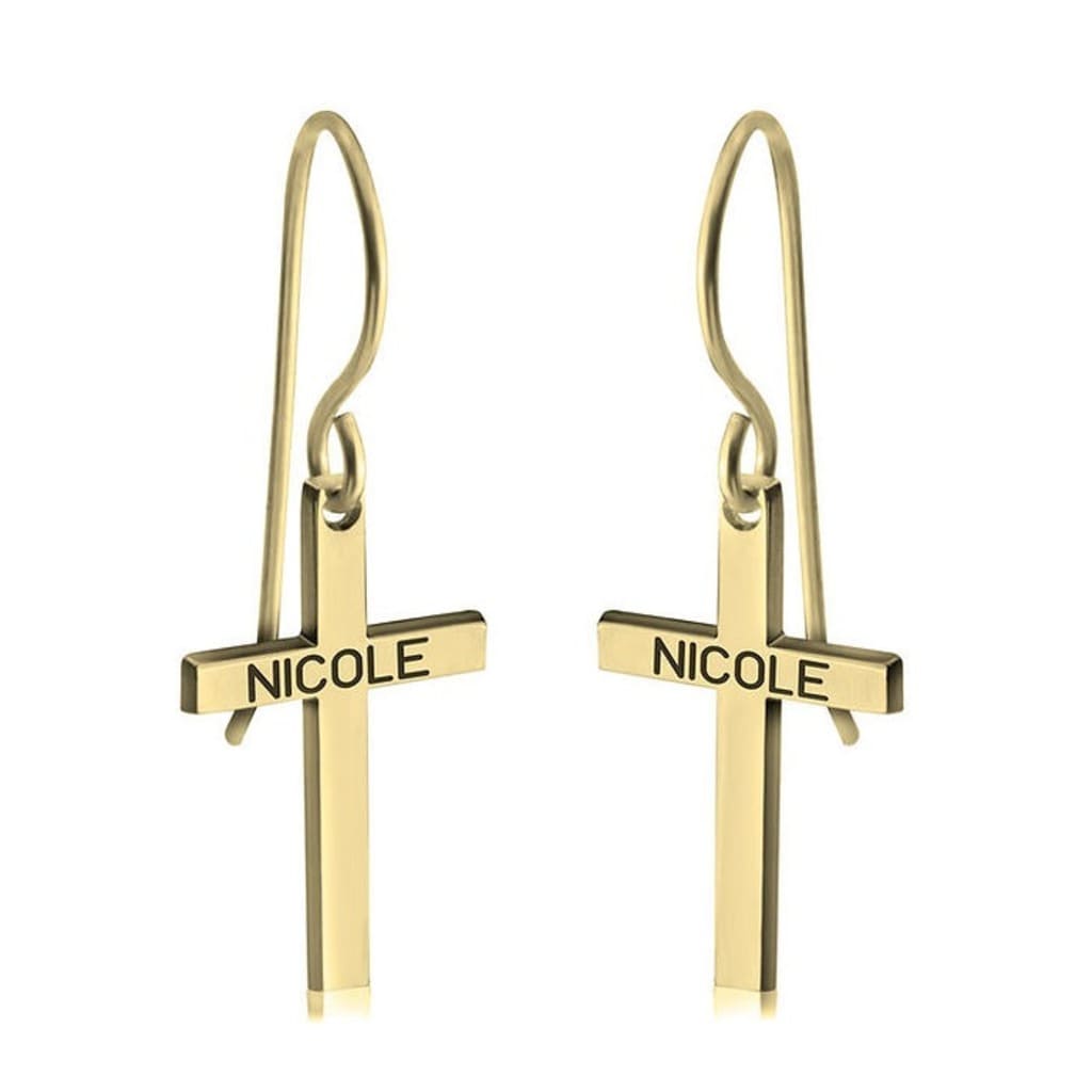 Gold cross-shaped earrings with 'NICOLE' engraving on a white background