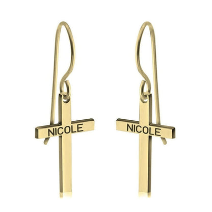 Gold cross-shaped earrings with 'NICOLE' engraving on a white background