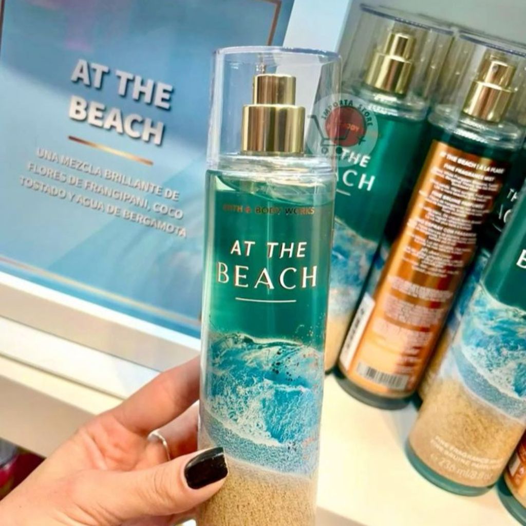 Hand holding a bottle of 'At the Beach' fragrance with more bottles in the background.