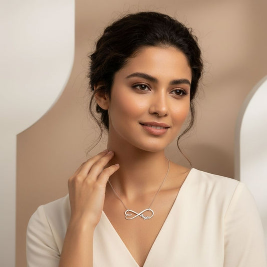 Woman wearing an infinity necklace against a neutral background