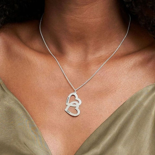 Silver heart-shaped pendant necklace on a person wearing a green top.