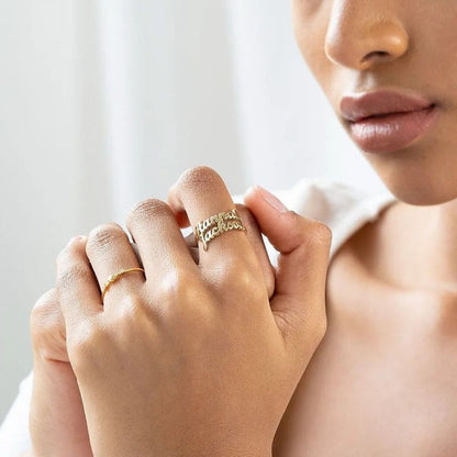 Close-up of a person wearing a gold ring with 'fashion' on a blurred background