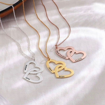 Three heart-shaped necklaces in silver, gold, and rose gold on a white fabric background.