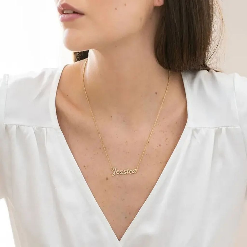 Gold name necklace on a person wearing a white blouse