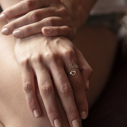 Close-up of a hand wearing a ring with 'Mia' on a blurred background