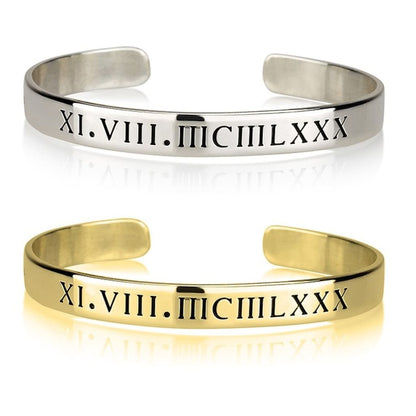Silver and gold bangles with Roman numeral engraving on a white background