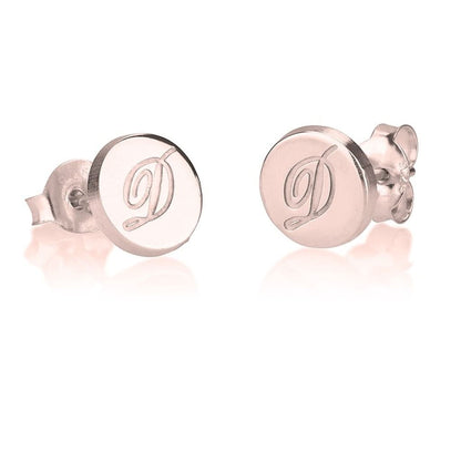 Pair of rose gold earrings with 'D' engraving on a white background