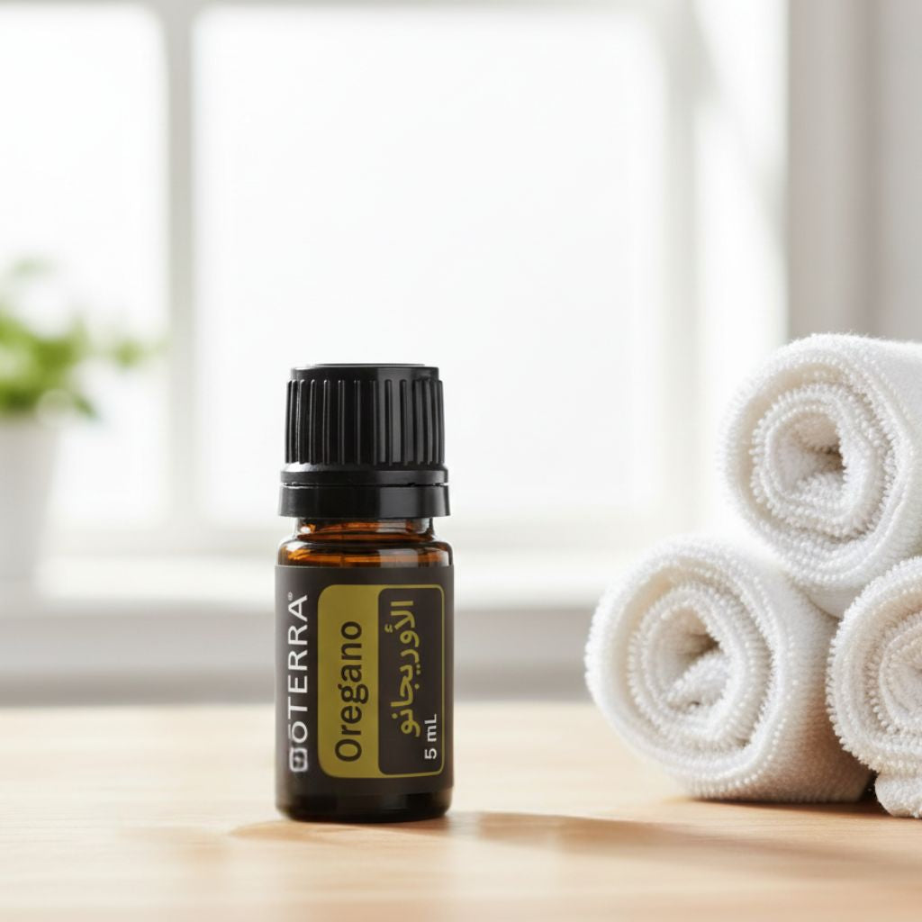 DoTERRA oregano essential oil bottle on a wooden surface with towels in the background