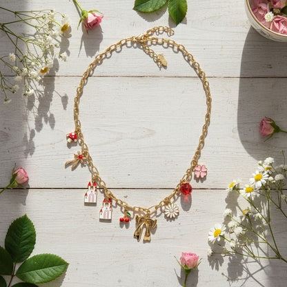 Gold necklace with charms on a wooden surface with flowers
