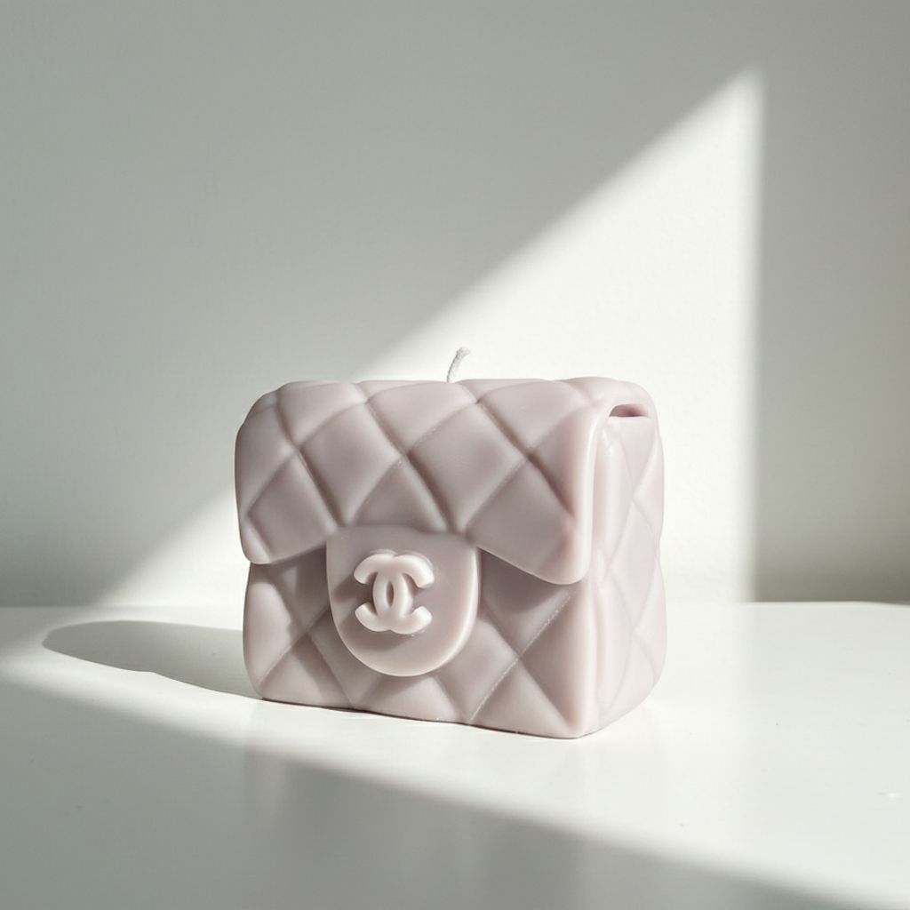 Pink quilted handbag-shaped candle with Chanel logo on a white surface
