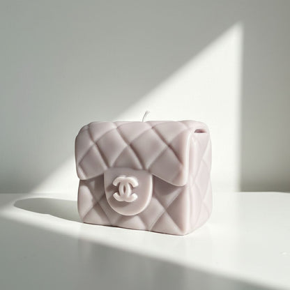 Pink quilted handbag-shaped candle with Chanel logo on a white surface