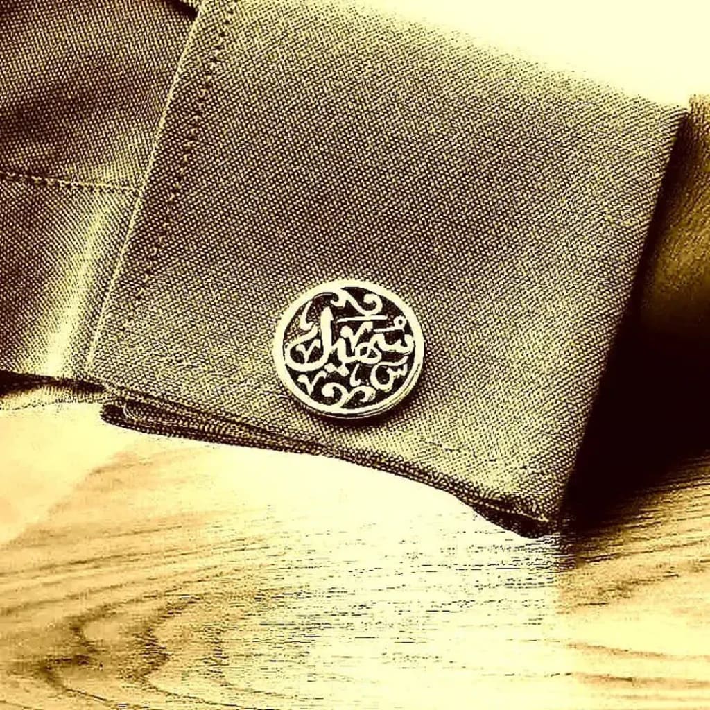 Arabic cufflinks on a grey sleeve