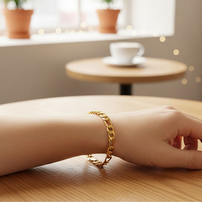 Gold chain bracelet on a wrist with a blurred cafe background