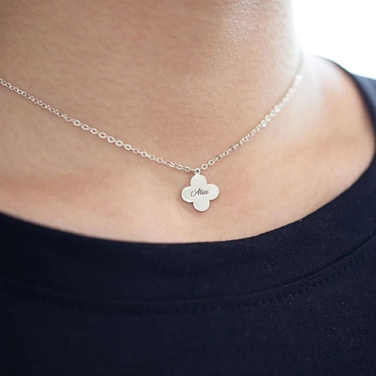 Silver necklace with a clover-shaped pendant on a person wearing a black shirt.