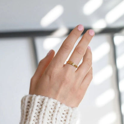 Hand wearing a gold ring with a blurred background