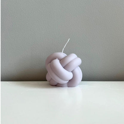 Knot-shaped candle on a plain background