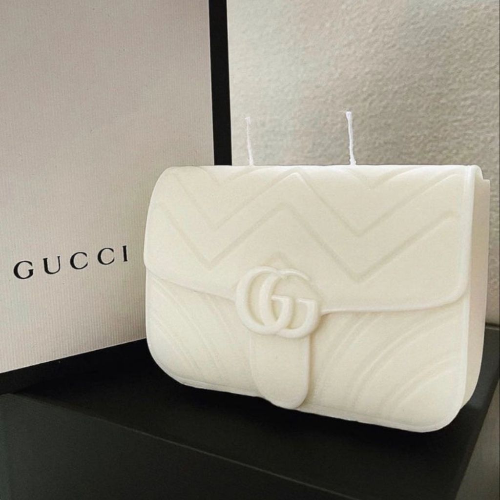 White quilted handbag with Gucci logo on a black surface with Gucci branding in the background.