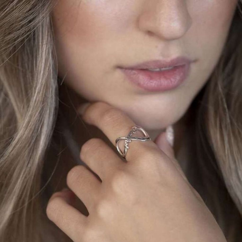 Close-up of a woman wearing a silver ring with a heart design.