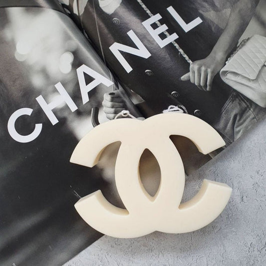 White Chanel logo earring on a blurred background with 'Chanel' branding.
