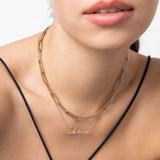 Gold chain necklace with a name pendant on a model against a neutral background