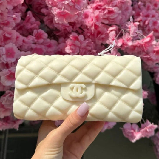 White quilted handbag with Chanel logo held in front of pink flowers