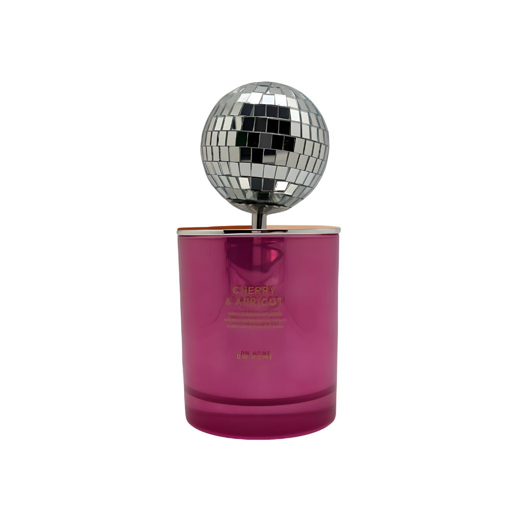 Pink candle with 'Cherry & Apricot' text next to a disco ball on a pink and beige background