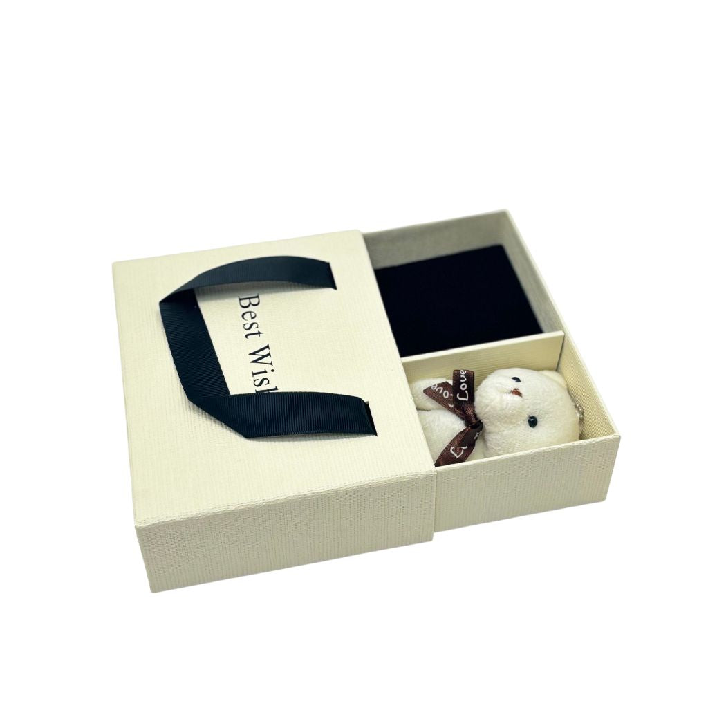 Gift set with a small teddy bear, black bow tie, and card in a box on a white background