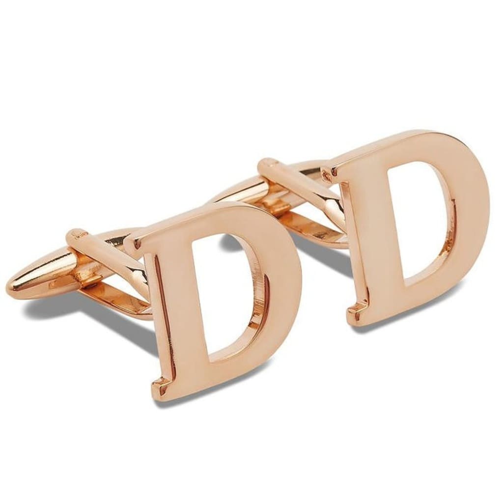 Rose gold cufflinks with 'D' initials on a white background